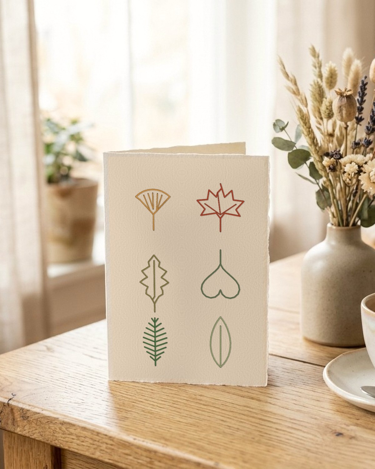 Pressed leaf paper embroidery card on a worktable